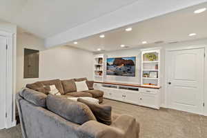 Living room featuring electric panel, light colored carpet, and recessed lighting