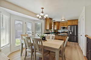 Dining area with a chandelier, light wood-style flooring, and a textured ceiling