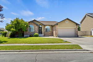 Single story home featuring stucco siding, an attached garage, driveway, a gate, and stone siding