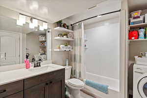 Bathroom featuring washer / clothes dryer, vanity, and shower / bath combo