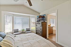 Bedroom with lofted ceiling, light colored carpet, ensuite bathroom, and ceiling fan