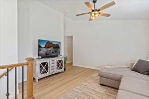 Living room with light wood-type flooring, ceiling fan, and lofted ceiling