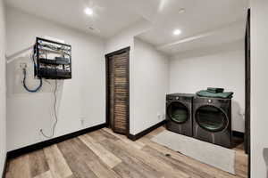 Laundry area featuring separate washer and dryer, wood finished floors, and recessed lighting