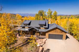 Chalet / cabin featuring a forest view, a porch, a standing seam roof, and an attached garage