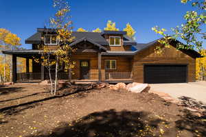 View of front facade with a porch, a standing seam roof, a metal roof, a garage, and driveway
