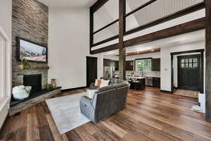 Living room with high vaulted ceiling, a stone fireplace, and dark wood-type flooring