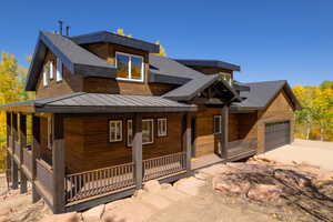 View of front of home featuring covered porch, a standing seam roof, a garage, a metal roof, and driveway