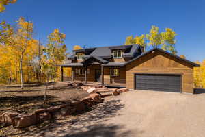 Rustic home featuring a standing seam roof, a porch, a metal roof, driveway, and a garage