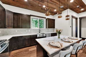 Kitchen with stainless steel appliances, wood ceiling, light wood-type flooring, a kitchen breakfast bar, and decorative backsplash