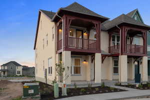 View of front of property with stucco siding, roof with shingles, and covered porch