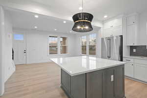 Kitchen featuring high end refrigerator, healthy amount of natural light, white cabinetry, light countertops, and recessed lighting