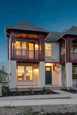 View of front of house with a balcony, stucco siding, and a shingled roof