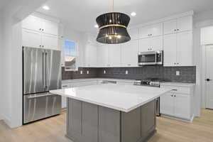 Kitchen with stainless steel appliances, light countertops, light wood-style flooring, tasteful backsplash, and recessed lighting