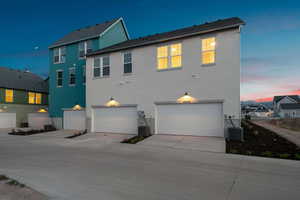 Back of house featuring stucco siding, a garage, and driveway