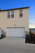 View of front facade featuring an attached garage, stucco siding, and concrete driveway