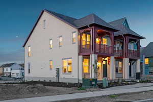 View of front of home featuring a balcony, a shingled roof, and stucco siding