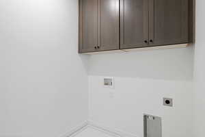 Washroom with electric dryer hookup, washer hookup, and cabinet space