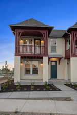 View of front of house featuring a balcony, stucco siding, and roof with shingles