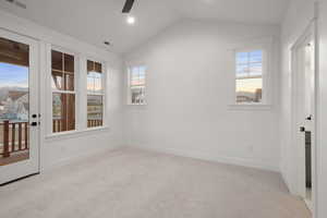 Spare room featuring a ceiling fan, vaulted ceiling, and carpet flooring