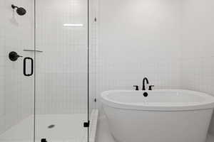 Bathroom with a stall shower, a freestanding bath, and tile walls