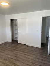 Unfurnished bedroom featuring dark wood finished floors and a closet