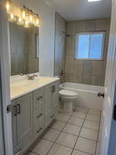 Bathroom featuring double vanity, tile patterned flooring, and washtub / shower combination