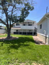 Back of property with ceiling fan and a lawn