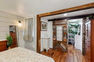 Primary bedroom view into walk in closet. Custom barn board frame and barn sliding door.