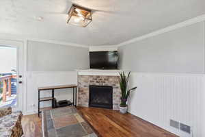 Living area with wood finished floors, wainscoting and gas fireplace.