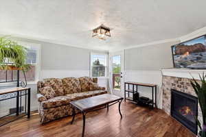 Living room with plenty of natural light, a wainscoted wall, wood finished floors, a brick fireplace, and crown molding. Deck entrance from the door in living room.