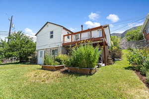 Back of property with a wooden deck and raised bed gardens