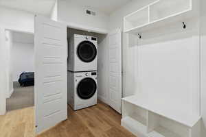Laundry room with estacked washer and dryer and light wood finished floors