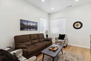 Living area with light wood-type flooring and recessed lighting