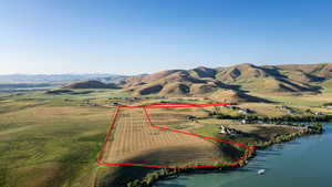 Aerial view of sparsely populated area with property parcel outlined and a water and mountain view
