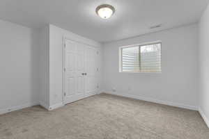 Unfurnished bedroom featuring carpet, a textured ceiling, and a closet