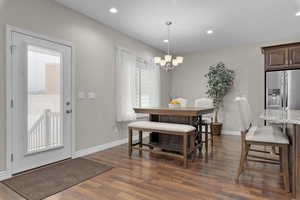 Dining space with healthy amount of natural light, dark wood-style flooring, a chandelier, and recessed lighting