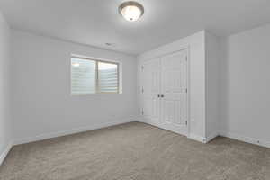 Unfurnished bedroom with carpet flooring, a closet, and a textured ceiling