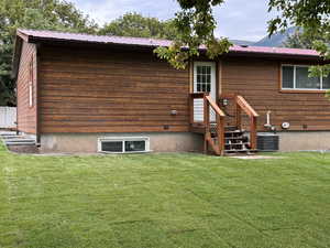 Rear view of property with a lawn and a metal roof