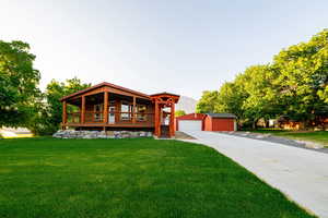 View of front of house featuring an outbuilding, a front yard, a detached garage, and a porch