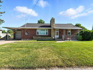 Single story home with concrete driveway, brick siding, a chimney, an attached garage, and a carport