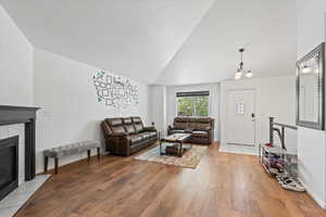 Living room featuring a tile fireplace, lofted ceiling, and light wood-style floors