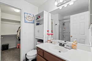 Bathroom with vanity, a shower with shower door, a spacious closet, and a textured ceiling
