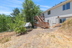 Rear view of property featuring stairway, a greenhouse, a deck, and an outbuilding