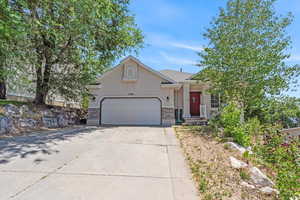 View of front of property with stucco siding, an attached garage, concrete driveway, and stone siding