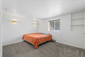 Carpeted bedroom featuring baseboards and a textured ceiling