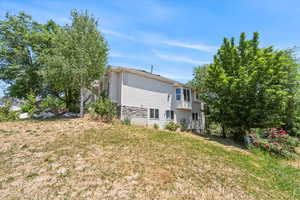 Rear view of property featuring a yard and stone siding