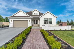 View of front of home with french doors, driveway, brick siding, a garage, and board and batten siding