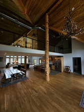 Living area with high vaulted ceiling, a wooden ceiling with exposed beams, hardwood / wood-style flooring, and a chandelier