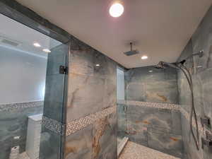 Bathroom featuring tile walls, a stall shower, and recessed lighting