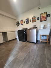 Laundry area with washer / clothes dryer, tile walls, a wainscoted wall, and dark tile patterned floors